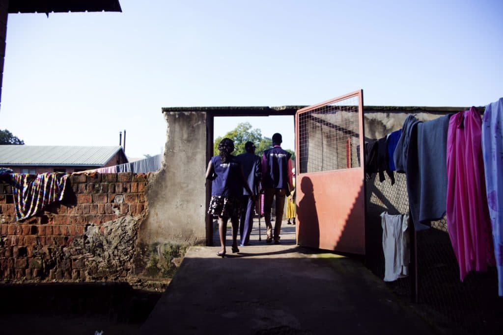 John is escorted out of Lacor hospital patients’ shelter by Refugee Law Project officers to go see the Doctor for a follow up treatment appointment. This is at about 10am in the morning.
