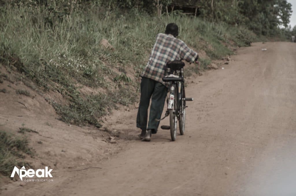 A man pushes his bicycle to retire at home after a day’s long work. Photo credit : Watsemba Miriam.